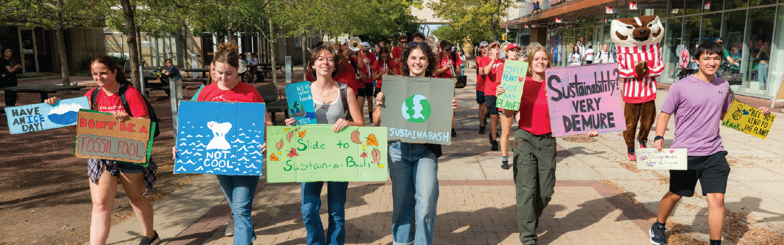 Students, UW Band, and Bucky walking with posters to sustain-a-bash