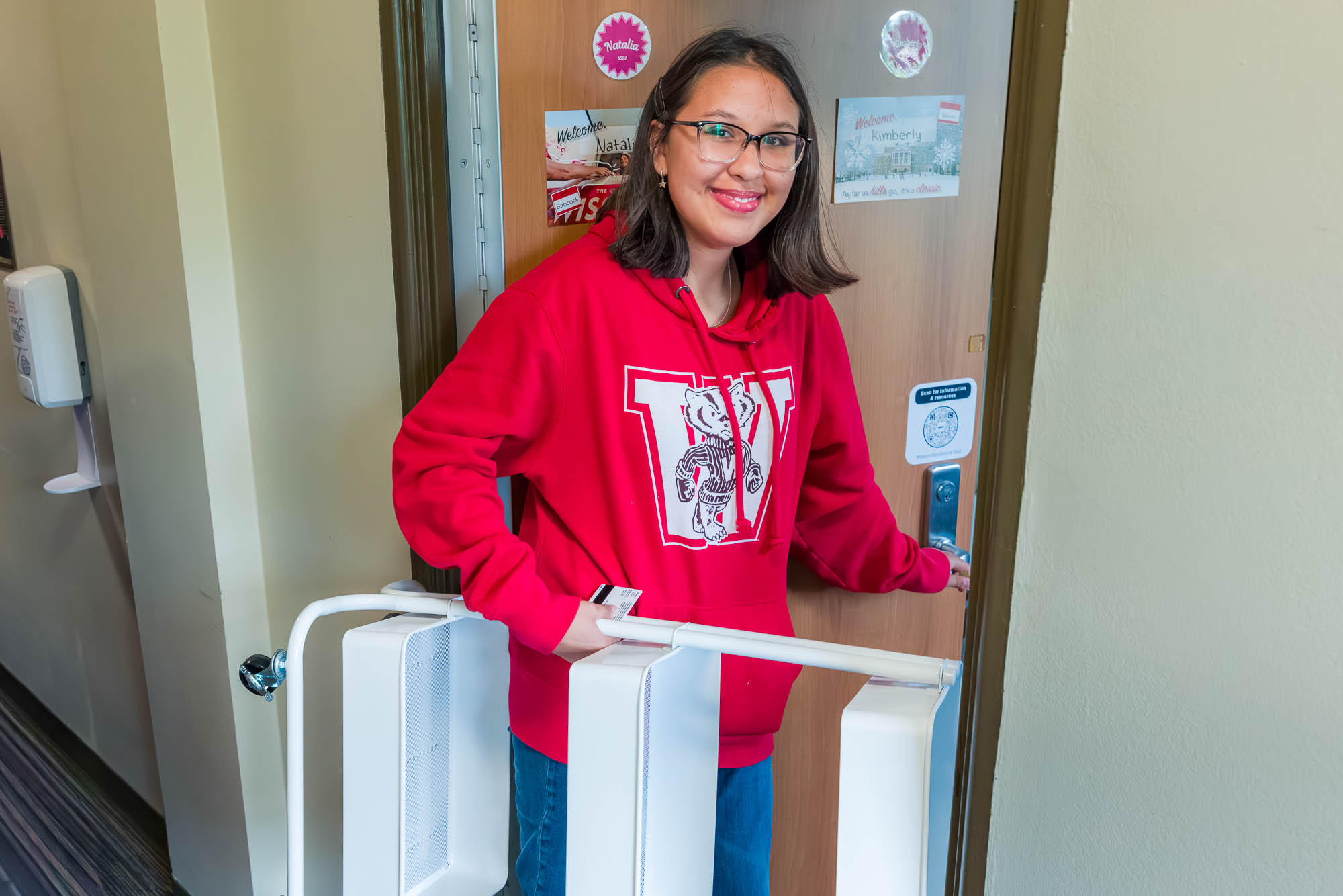A person in the doorway of their residence hall room with a storage caddy