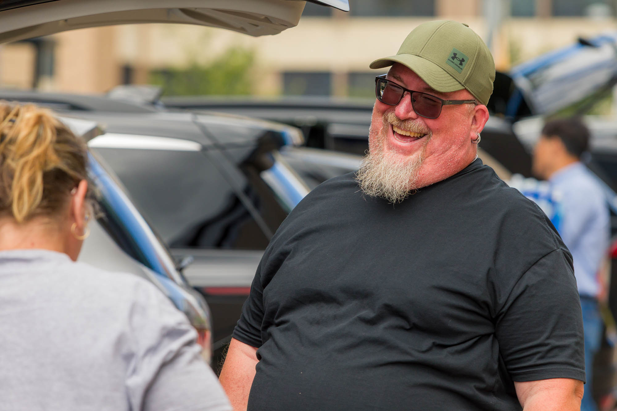 A person smiles behind their car