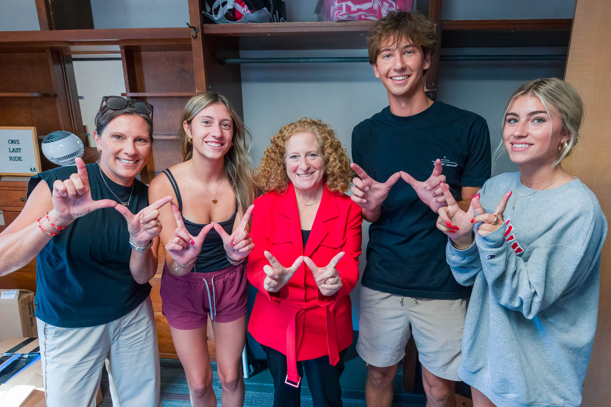 Five people pose for a photo while making "W's" with their hands