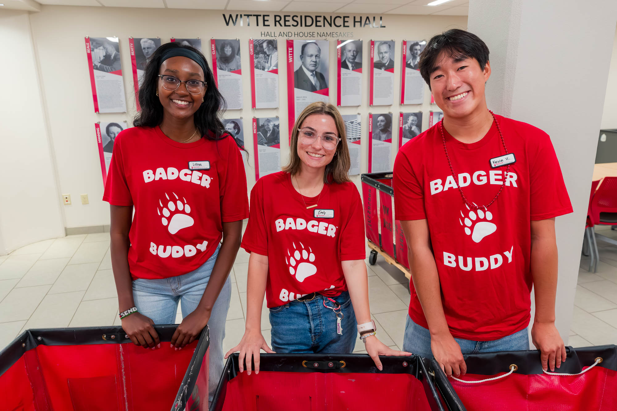 Three people pose for a photo in front of storage carts