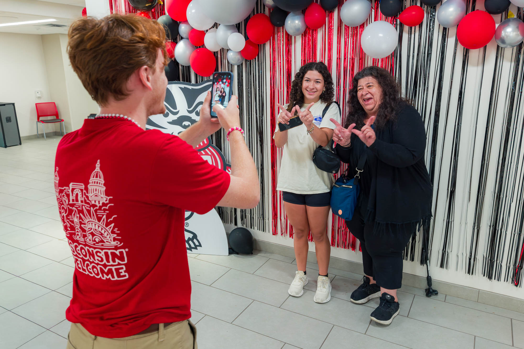 Two people pose for a photo while a third person takes their picture with a phone