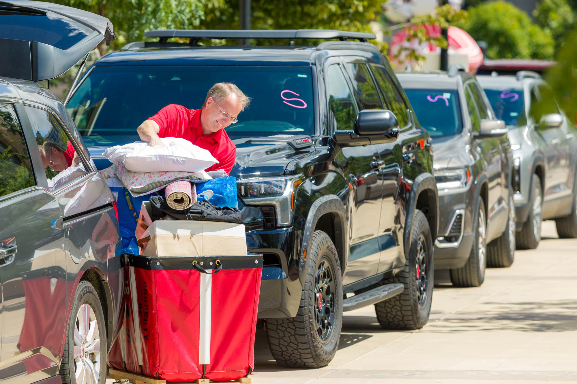 A person loading things into a cart with vehicles in the background