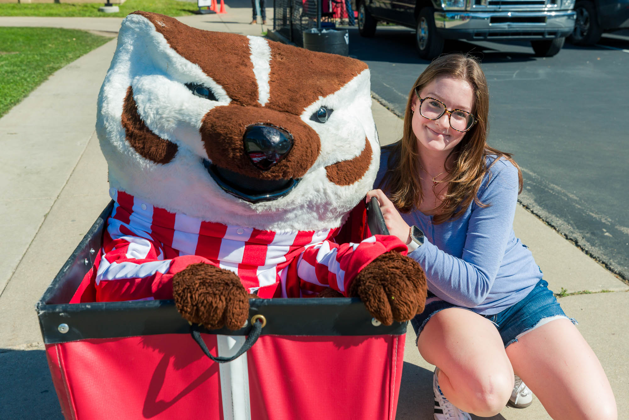 A person kneeling next to a storage cart with Bucky inside it