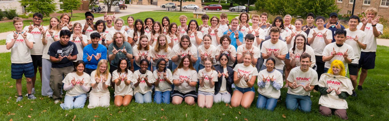 A group of students posing for a photo while making the letter "W" with their hands