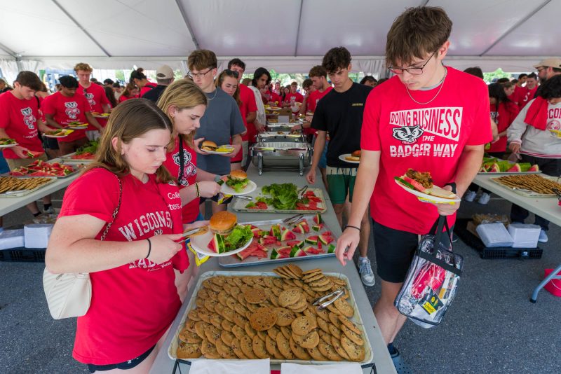 People take food from a buffet line under a tent