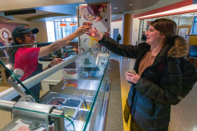 Student worker handing a customer an acai bowl at The Bean and Creamery