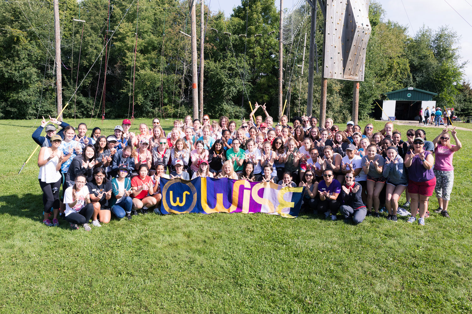 WISE residents pose with a banner of their name following a ropes course