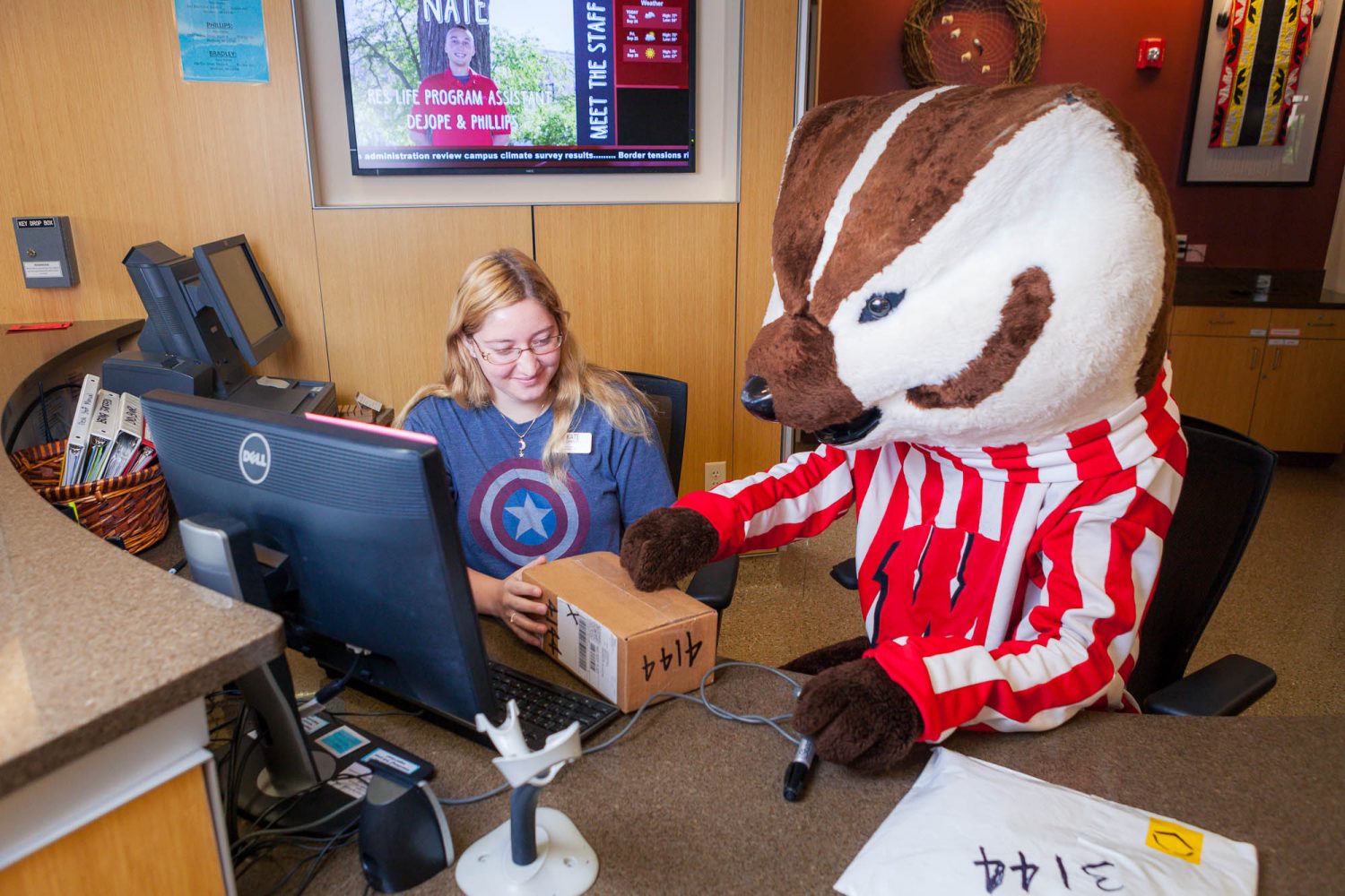 Bucky assisting a hall desk staff with checking-in a package