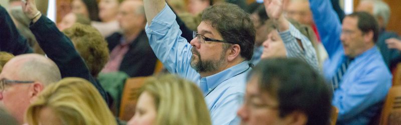 Audience participants raise hands to ask questions