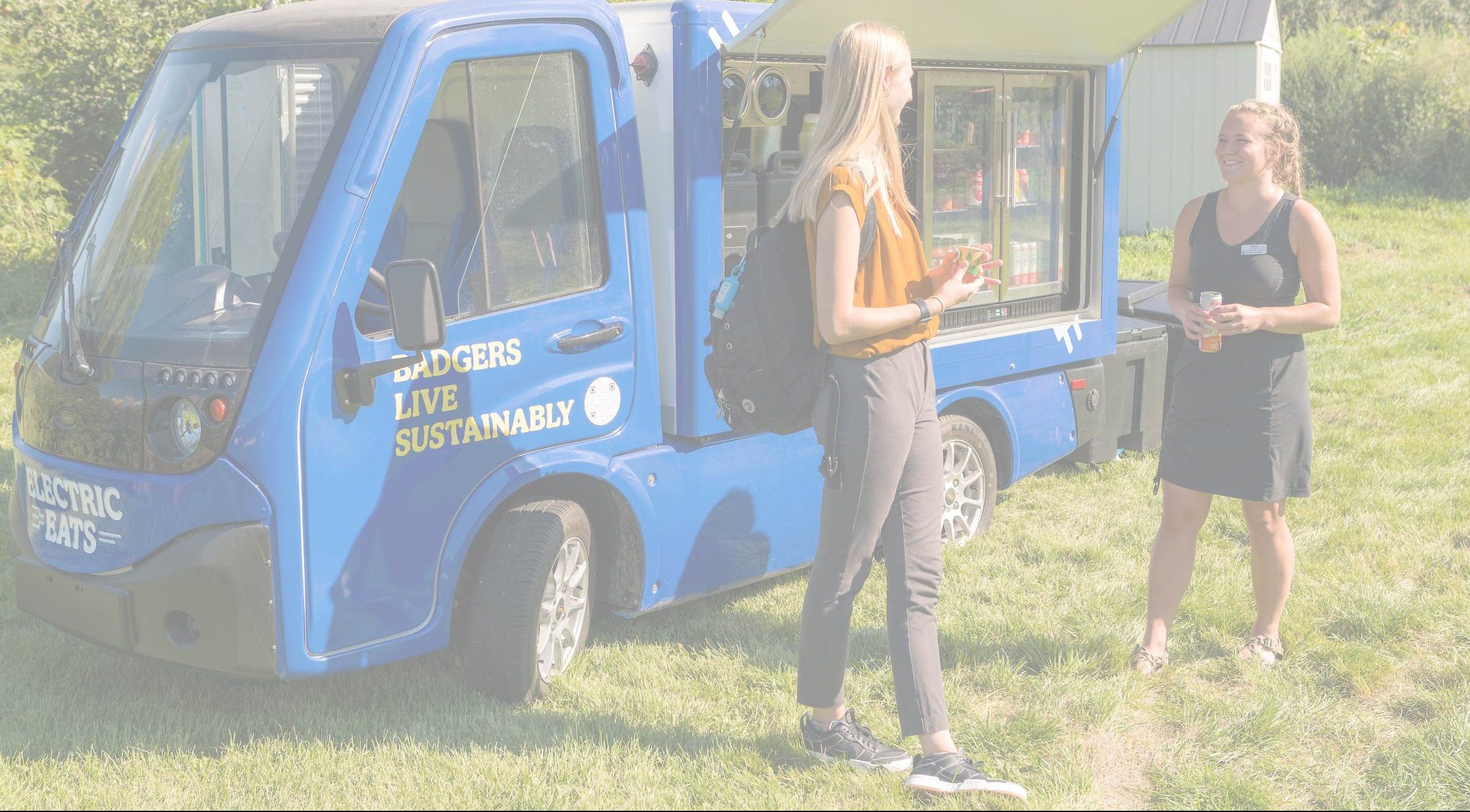 Two people chat in front of the Electric Eats food truck at the University Apartments Community Garden