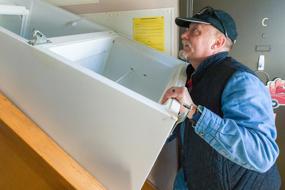 A UA staff member carrying a refrigerator up a set of stairs