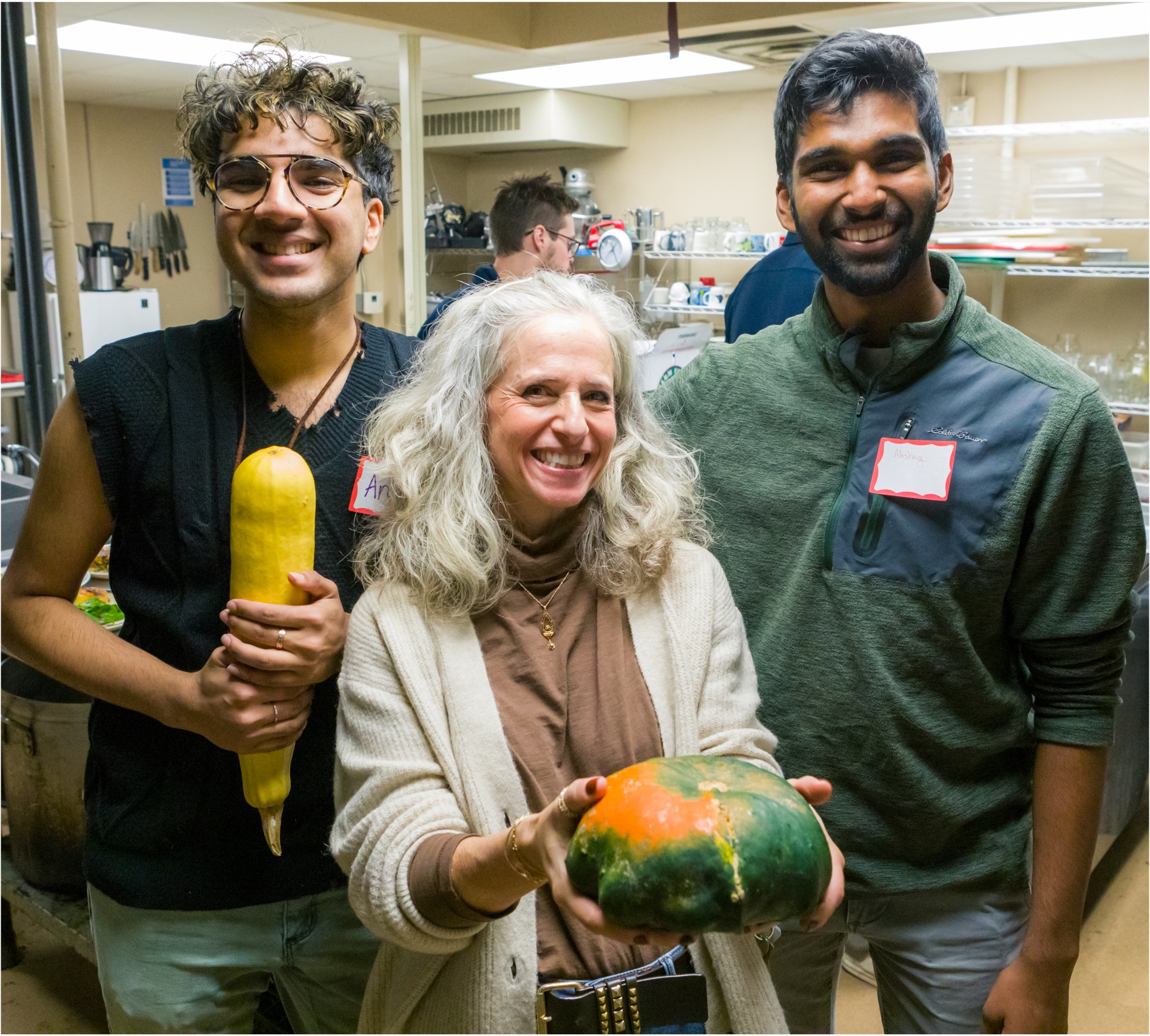 Three people pose for a photo holding produce