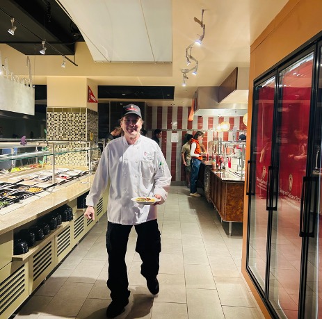 A Dining staff member carrying a dish in Liz's Market