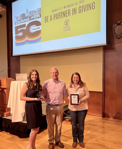 Staff posing for a group photo with a Partners in Giving award