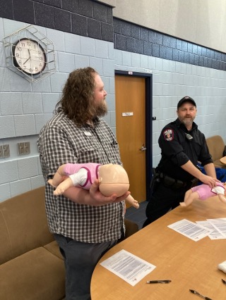 A UA staff member holding a doll as a UWPD officer looks on