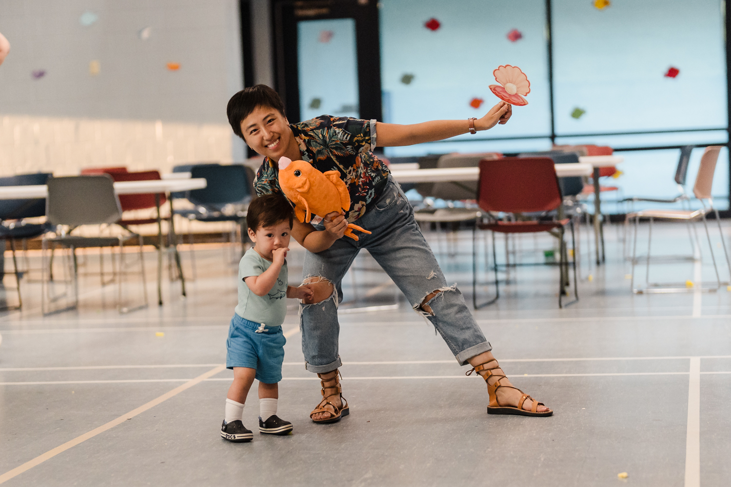 An adult and a young child posing for a photo with an orange fish cutout