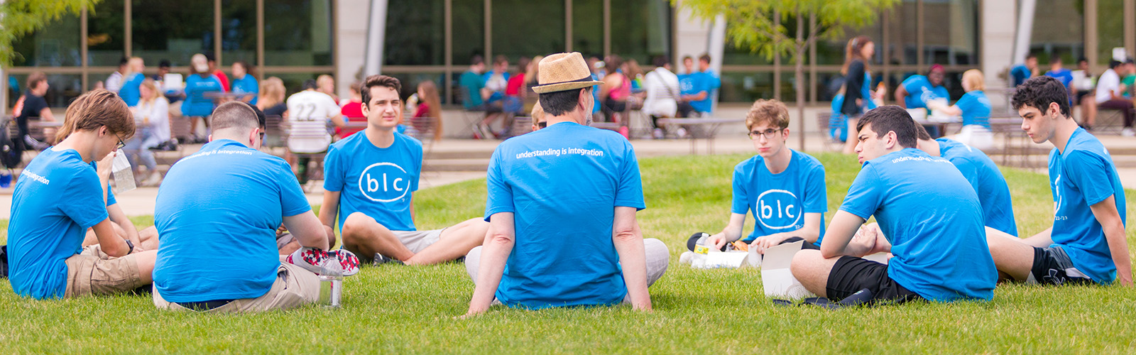 Students and faculty sit on the lawn outside Dejope Residence Hall for a discussion`