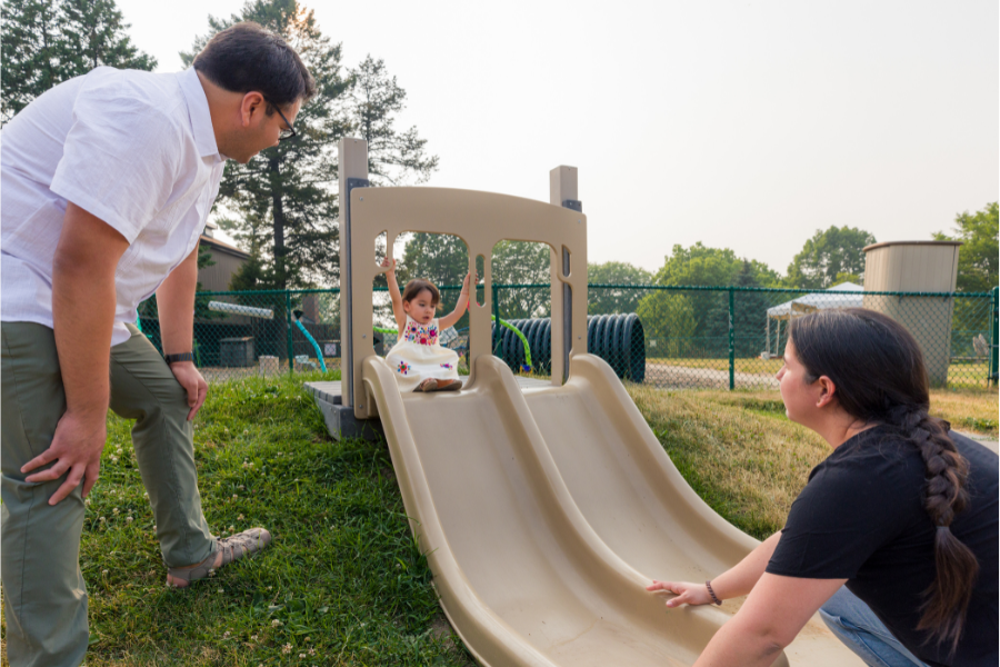 Child going down slide as parents watch at Eagle Heights outdoor recreation area.