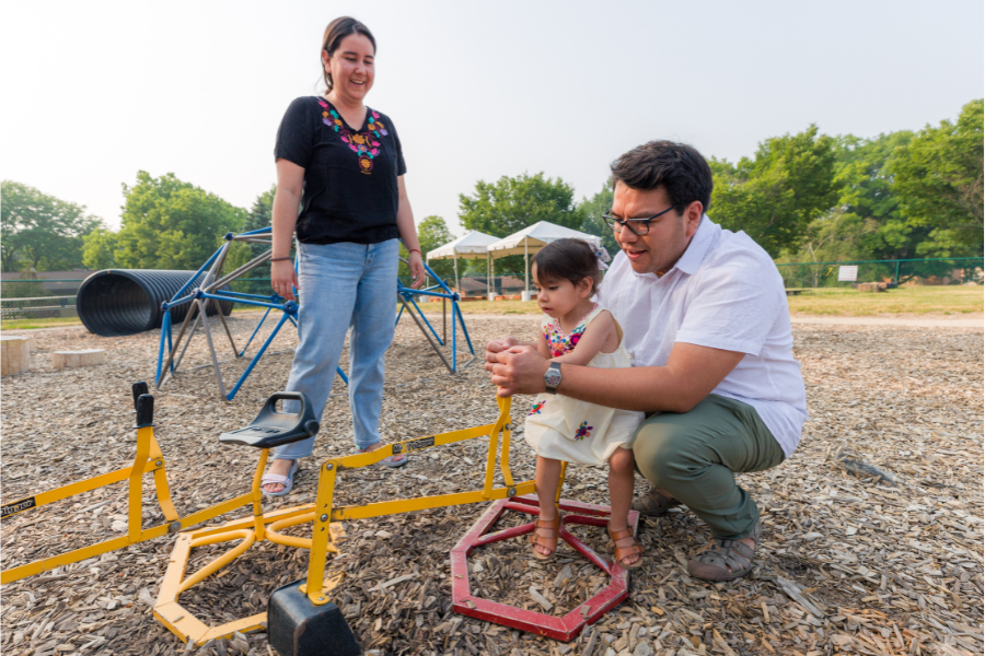 Parents playing with child at outdoor recreation area in Eagle Heights.