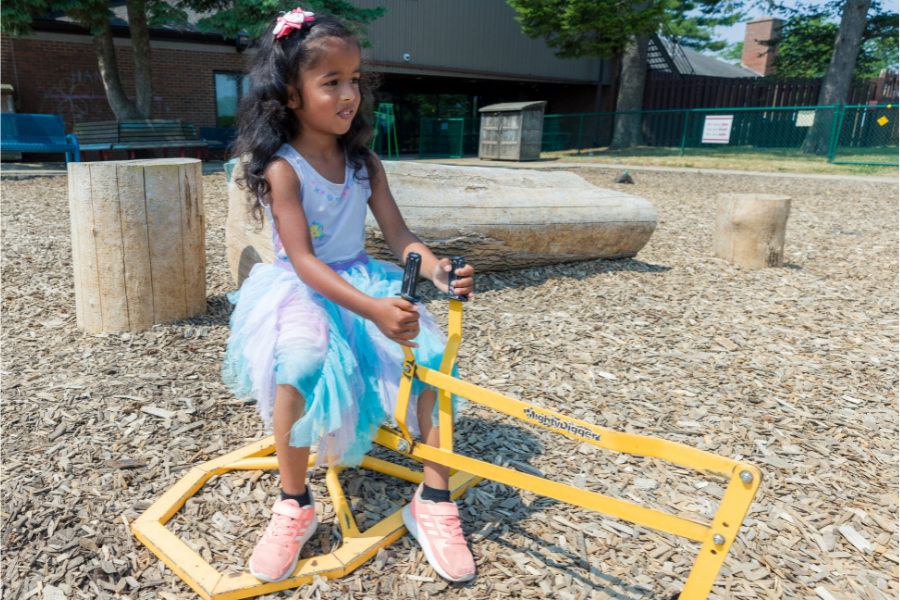 Little girl playing at an outdoor play area in University Apartments.