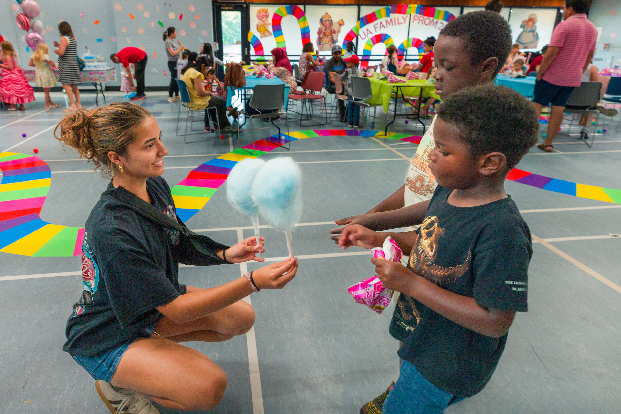 Two boys getting cotton candy from a women