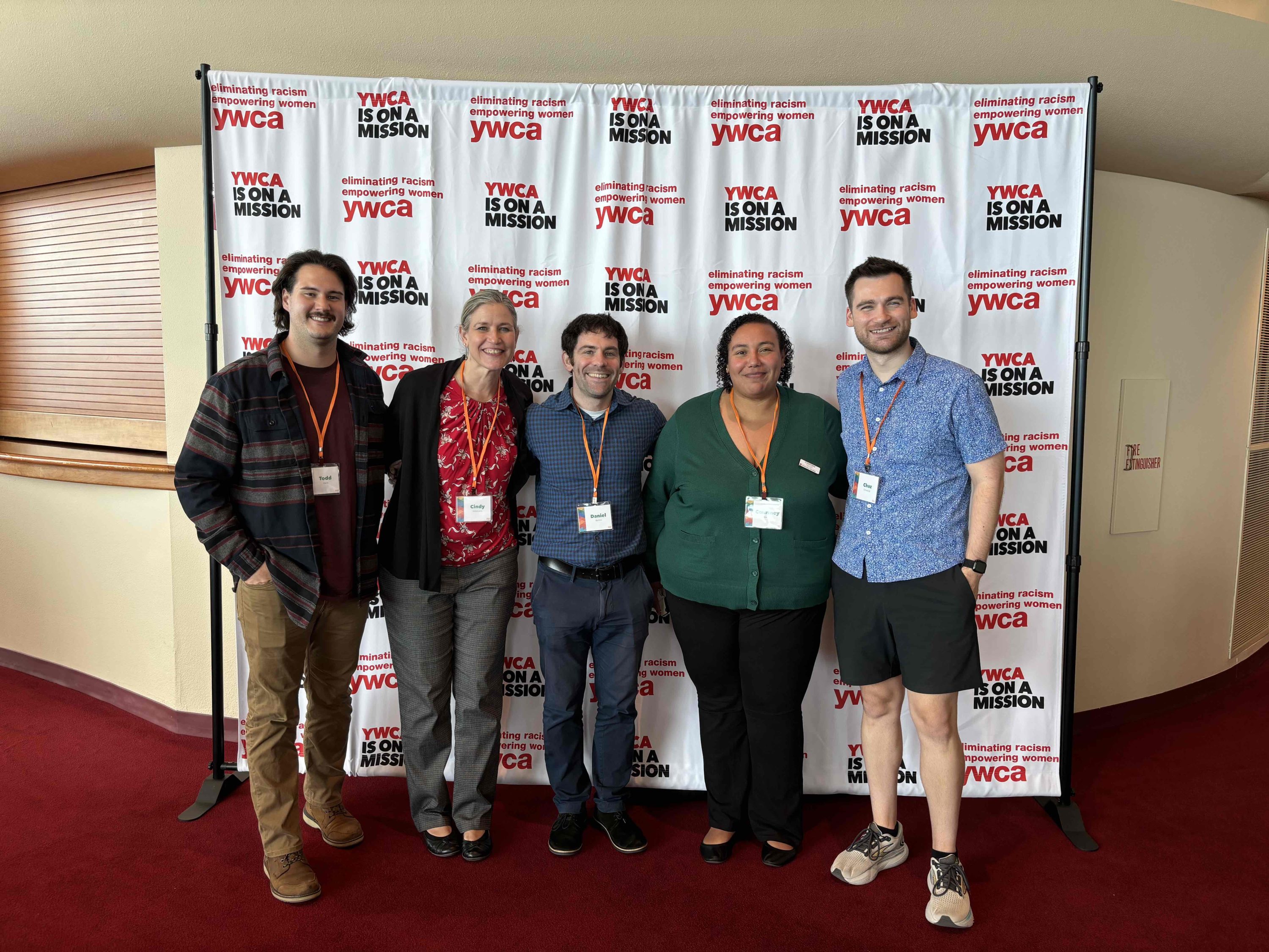 Five professionals smiling at the camera in front of a backdrop