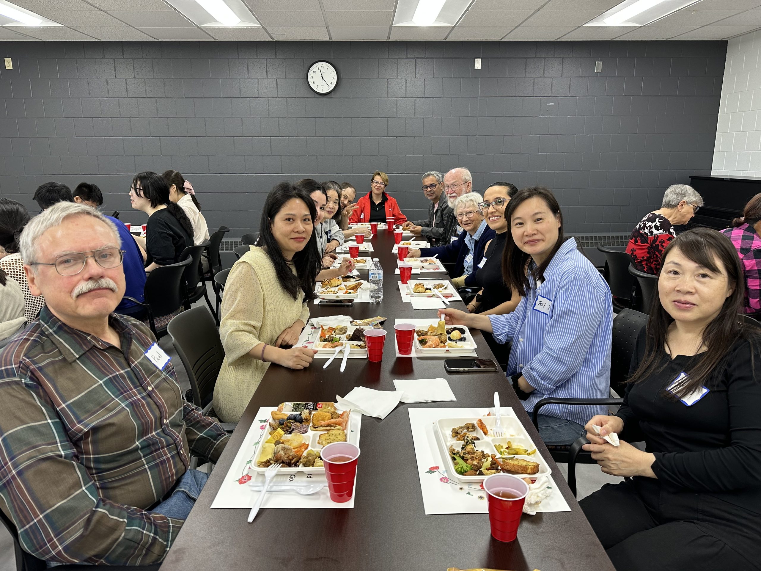 Group of people eating potluck food at a table