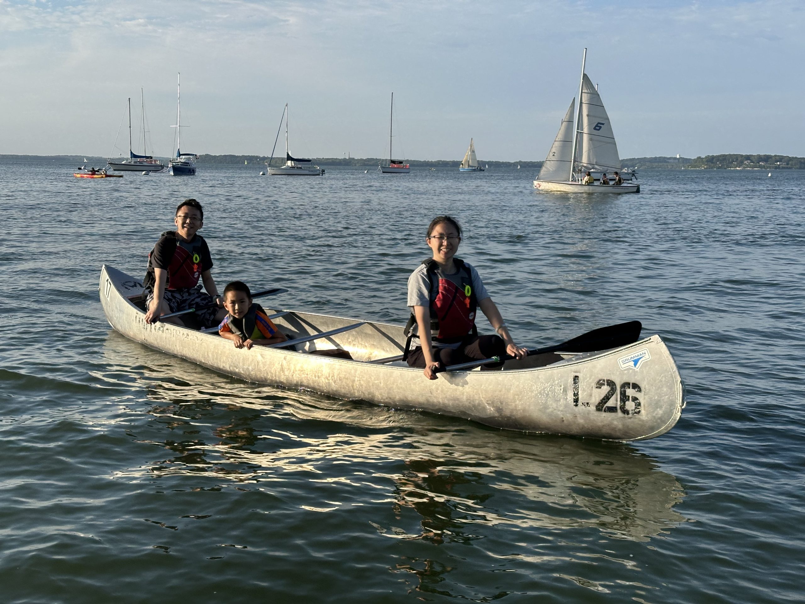 Three people in a canoe smiling at camera