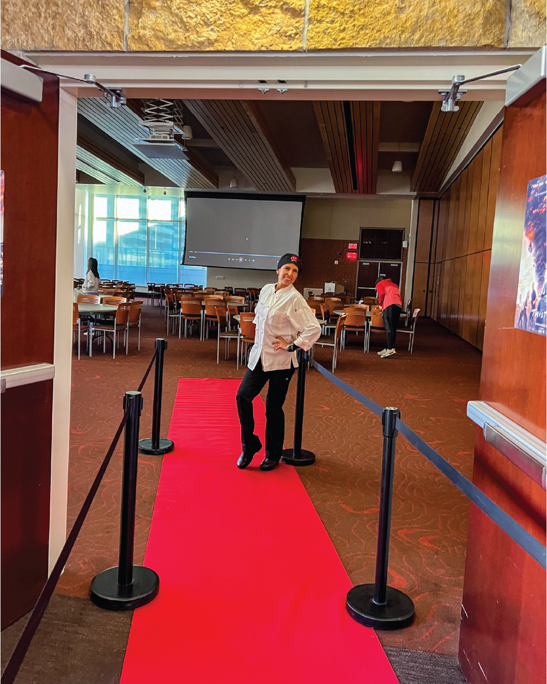 Staff member posing on red carpet at Dinner and a Movie event Gordon