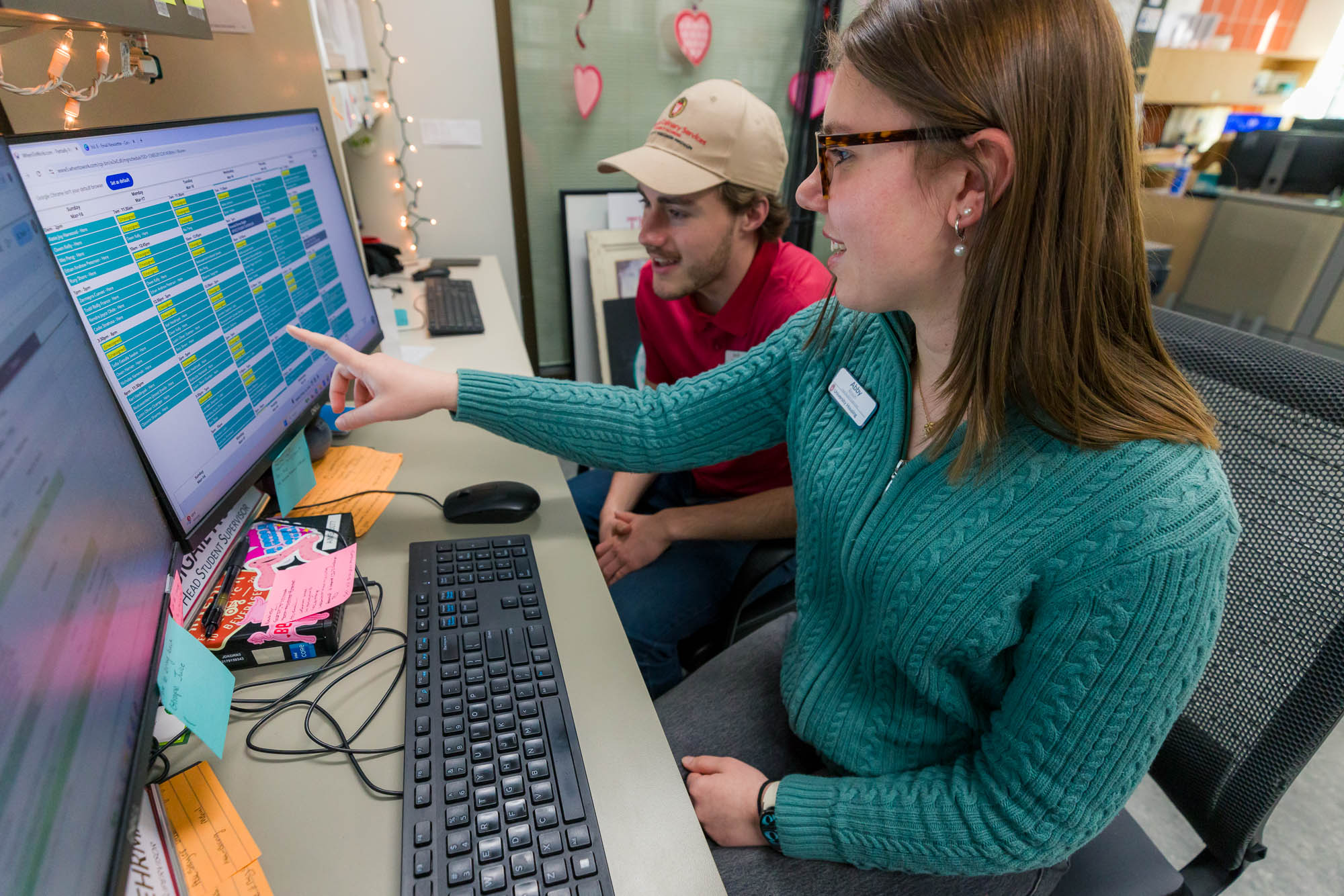Abby Rosin shows another student employee a schedule on a computer at Gordon.