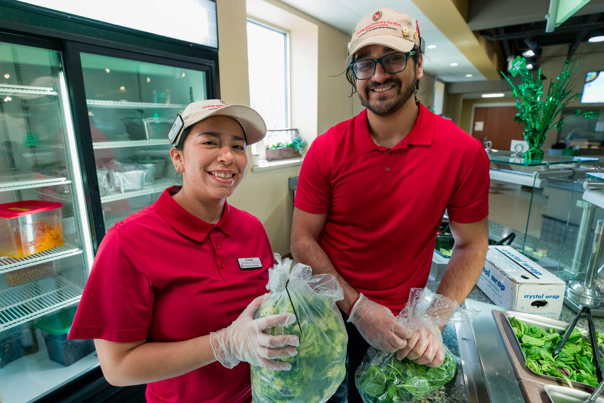 Kshitij Pandey poses for a photo with another student employee while restocking the Great Greens station in Rheta's Market.