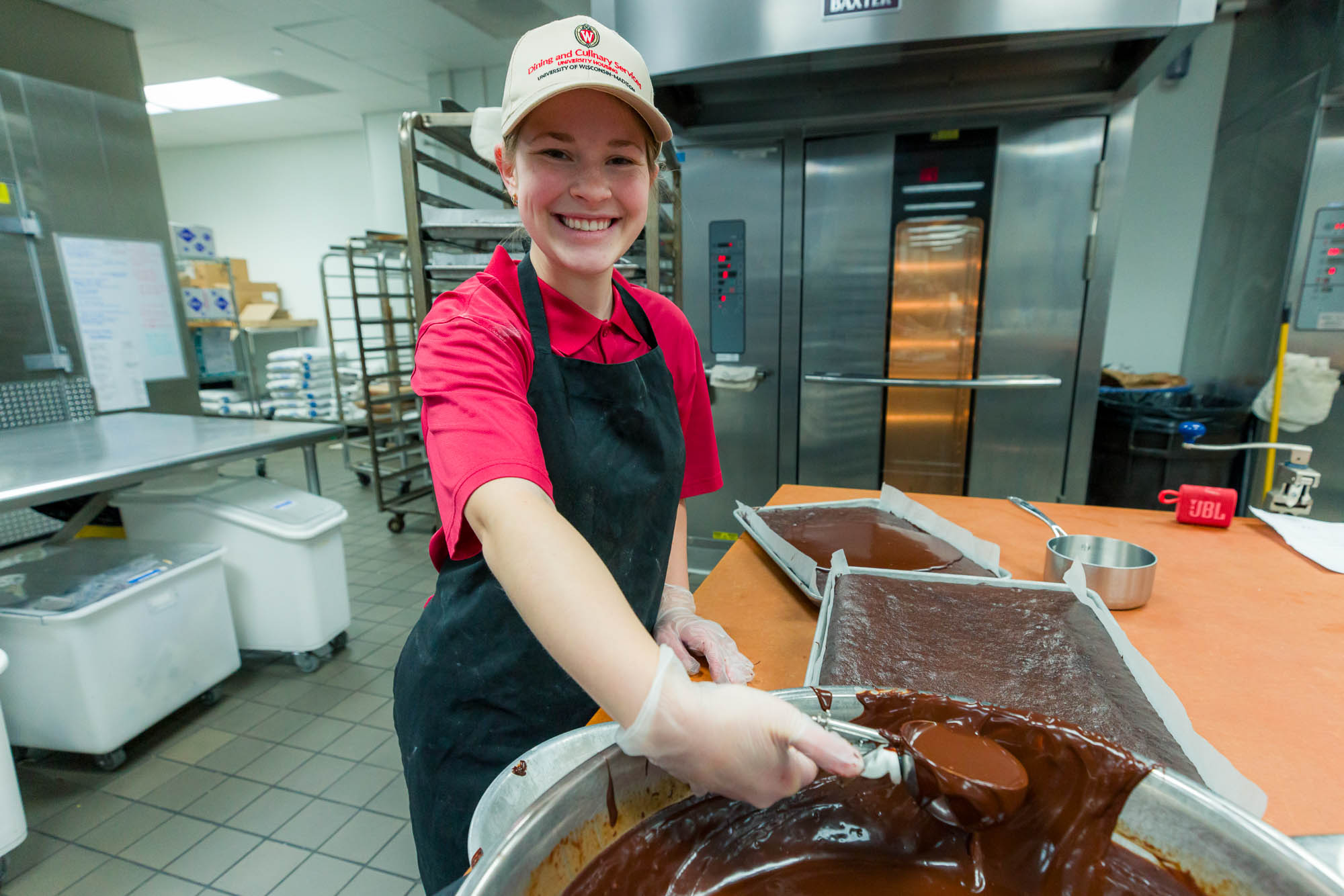 Emma Zeller scoops chocolate frosting in the kitchen at Gordon Dining & Event Center.