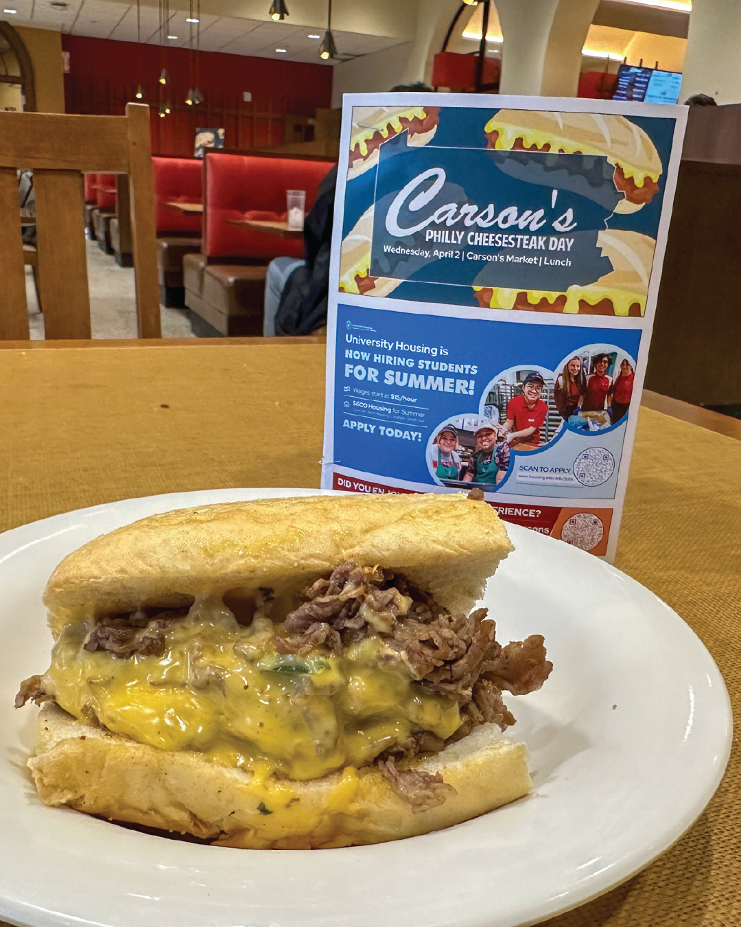 Philly Cheesesteak on plate with event sign behind