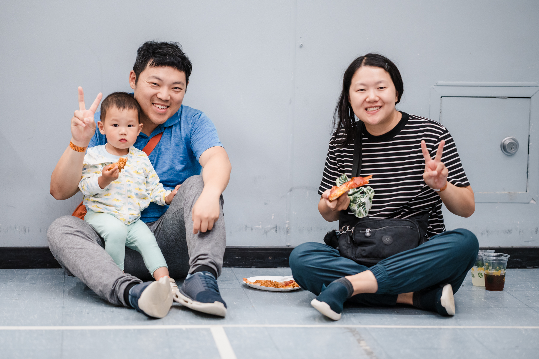 Two people giving peace sign with small child