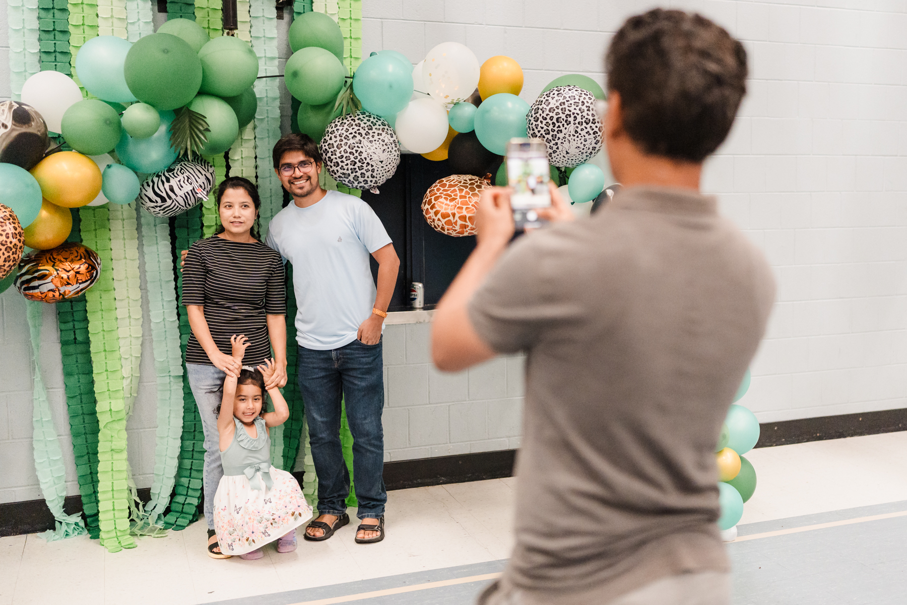 Family of man and women with daughter getting photo taken with backdrop