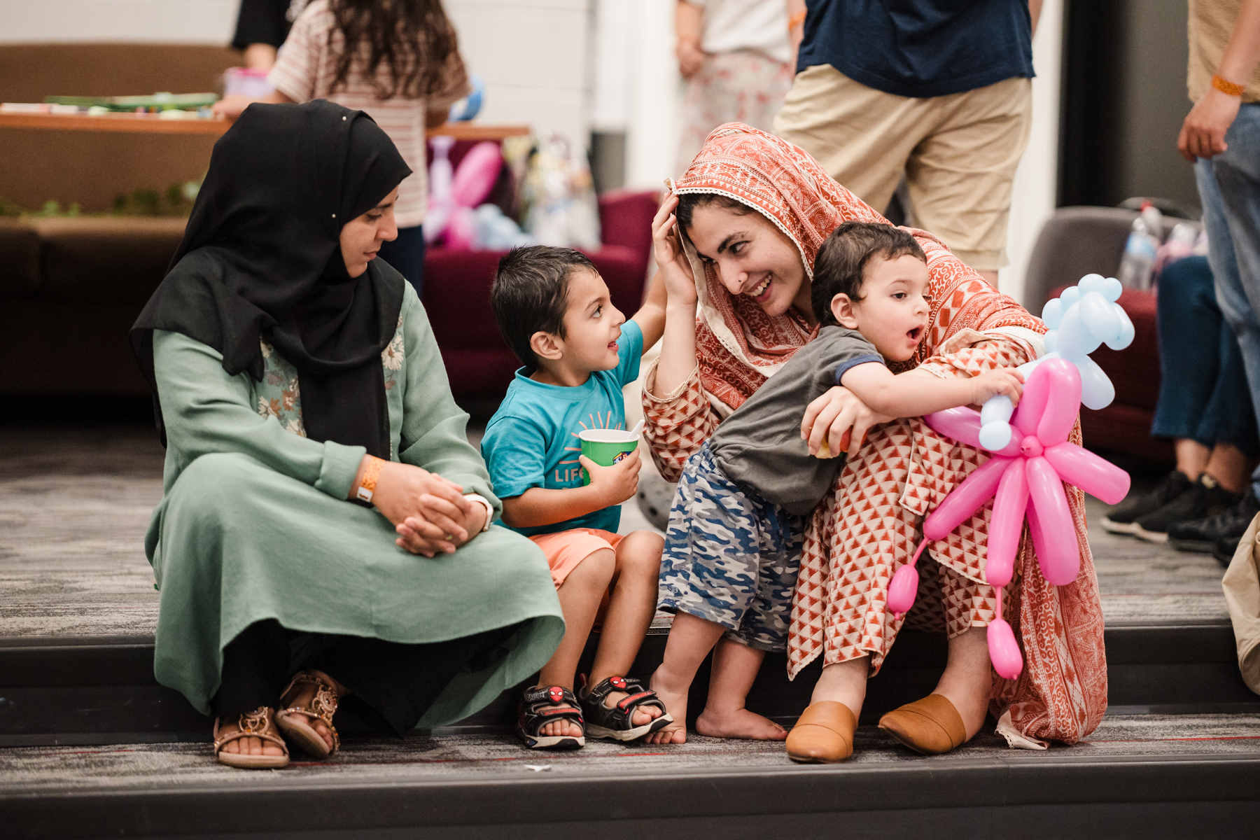 Two women with children smiling and sitting