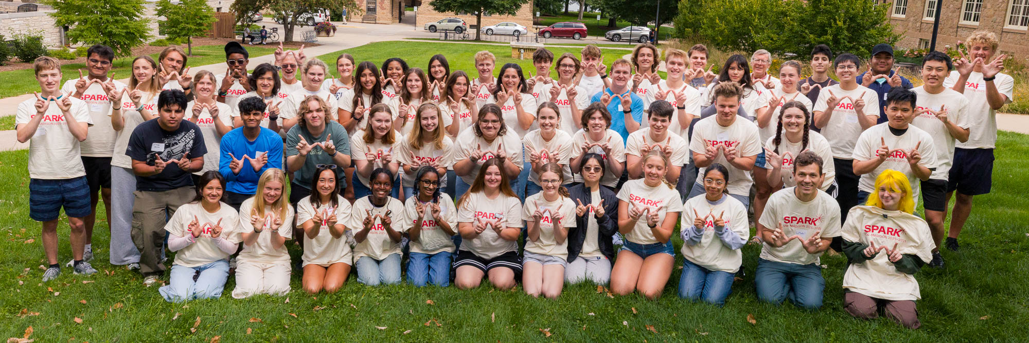 A group of students posing for a photo while making the letter "W" with their hands