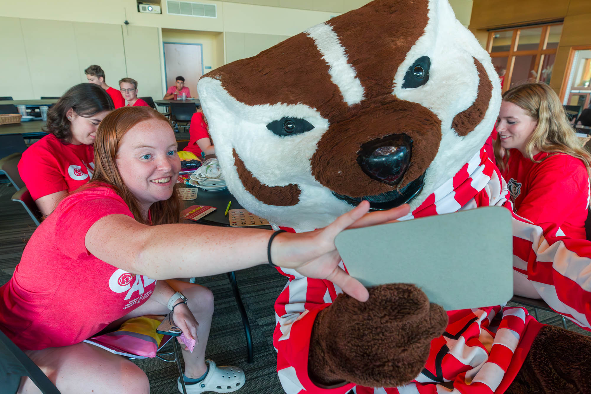 A person and Bucky Badger hold up a bingo card