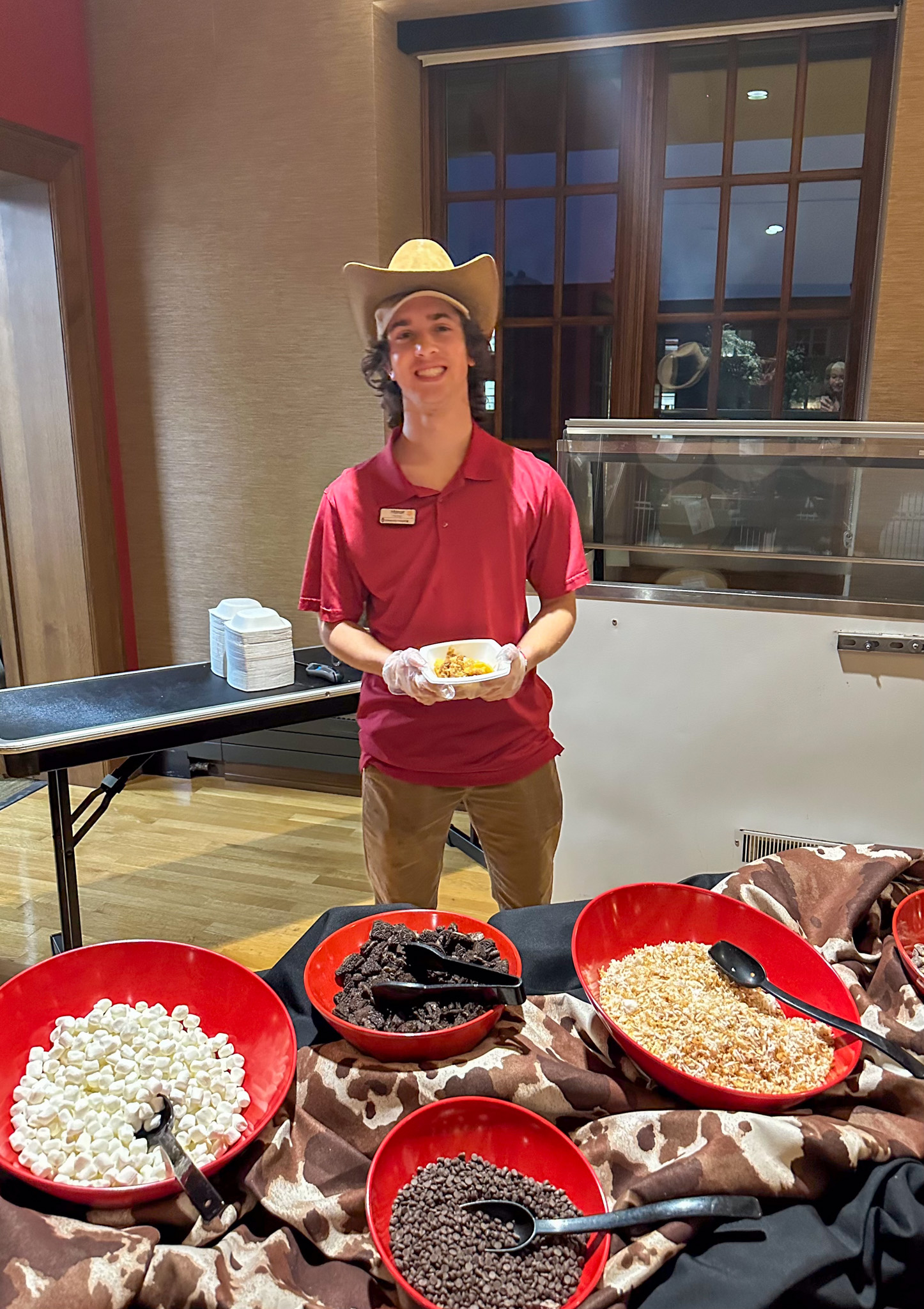 Student employee poses with cowboy hat at The Western Hoedown special event at Carson's Market