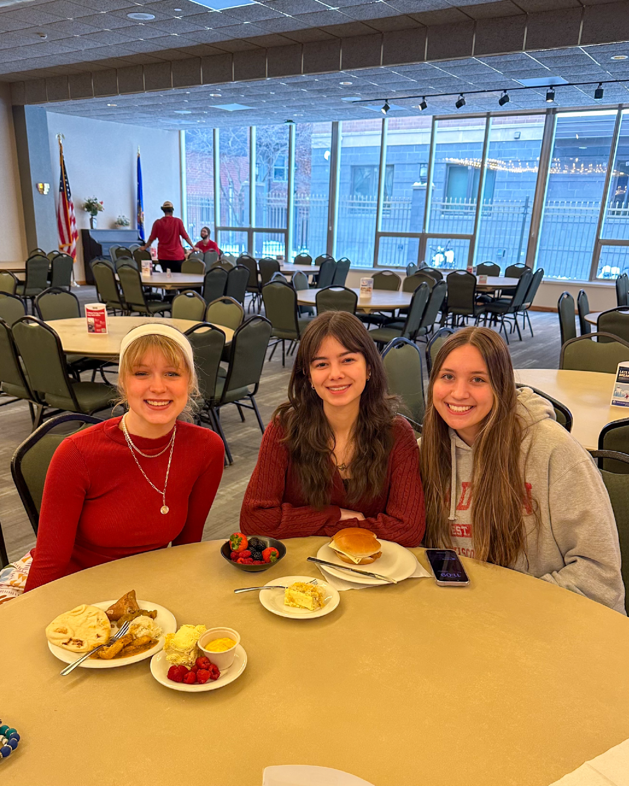 Three students smile for photo sitting at a table at Lowell during the Mango Overload event