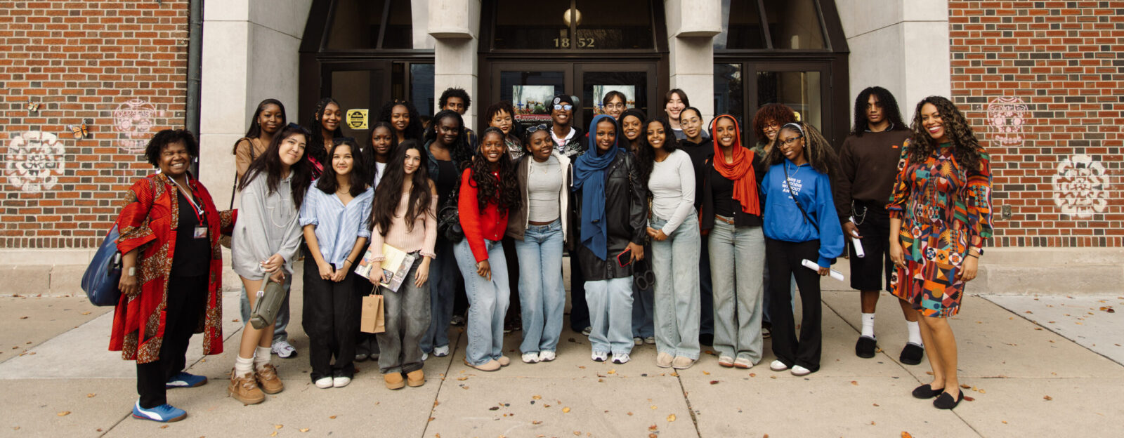 A large group of people pose in front of a building.