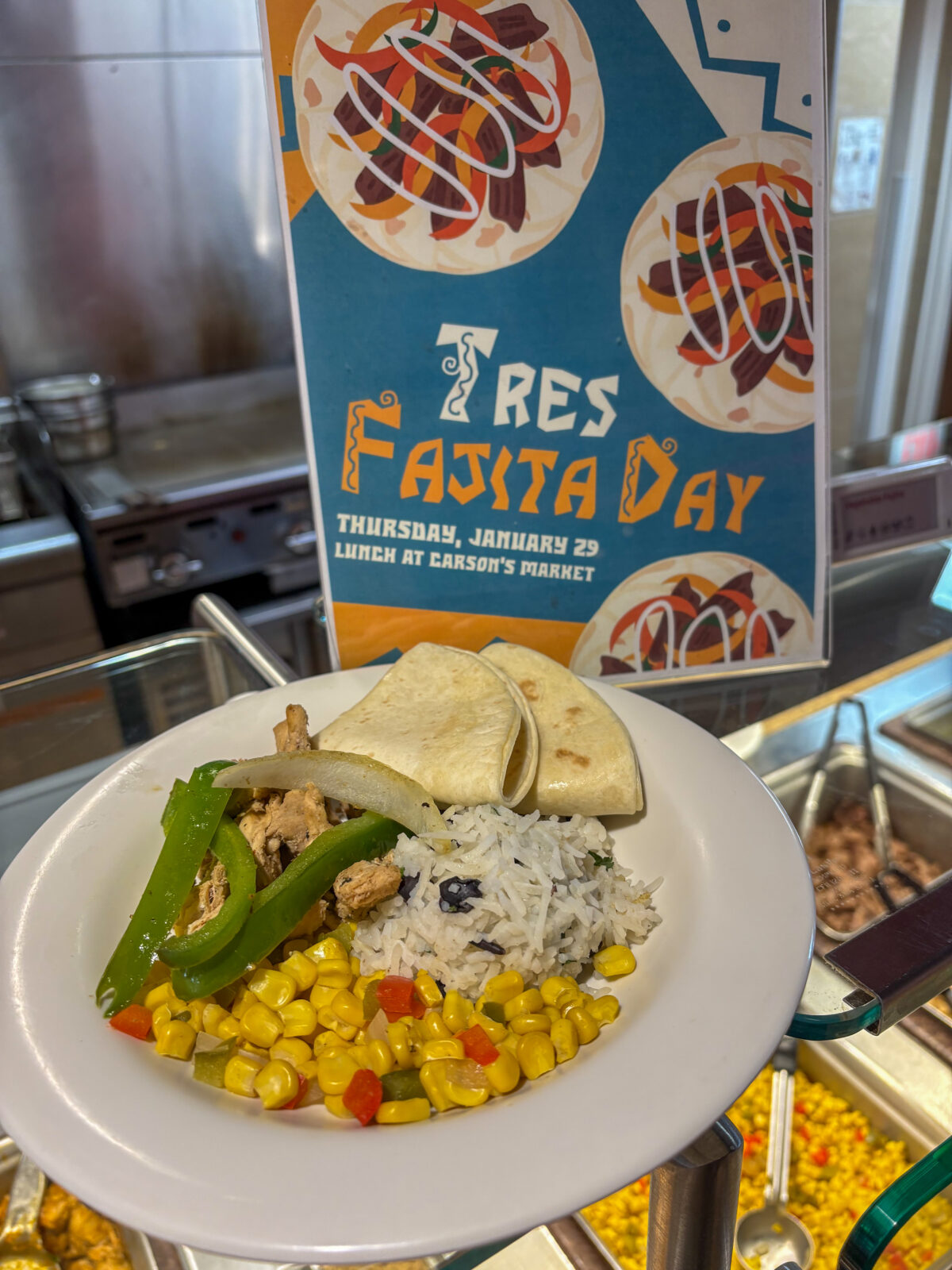 A plate of fajitas, corn, rice, and tortilla with a Tres Fajita Day sign