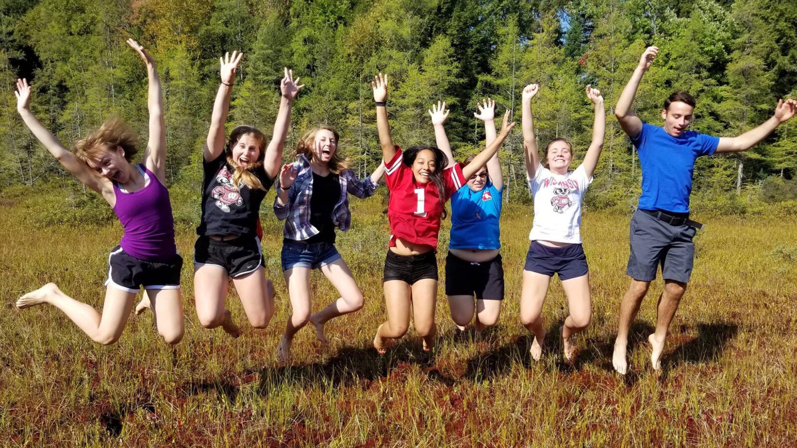 Seven people are photographed in mid-air as they jump in a bog.