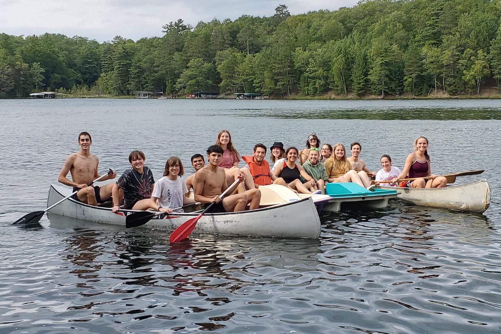 A group of people pose while canoeing on a lake.