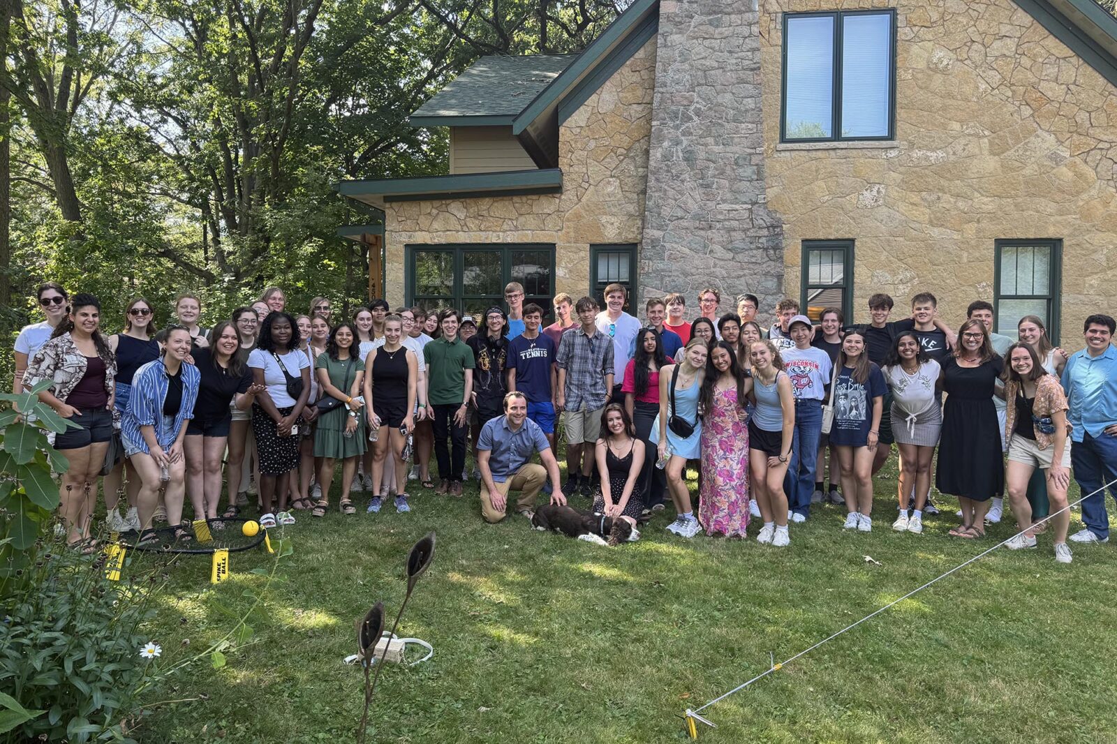 A large group poses in front of a house.