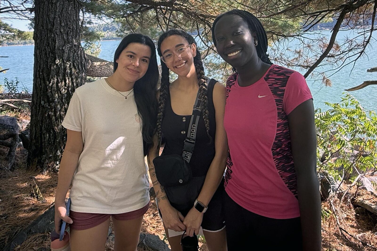 Three people pose in front of trees and Devil's Lake.