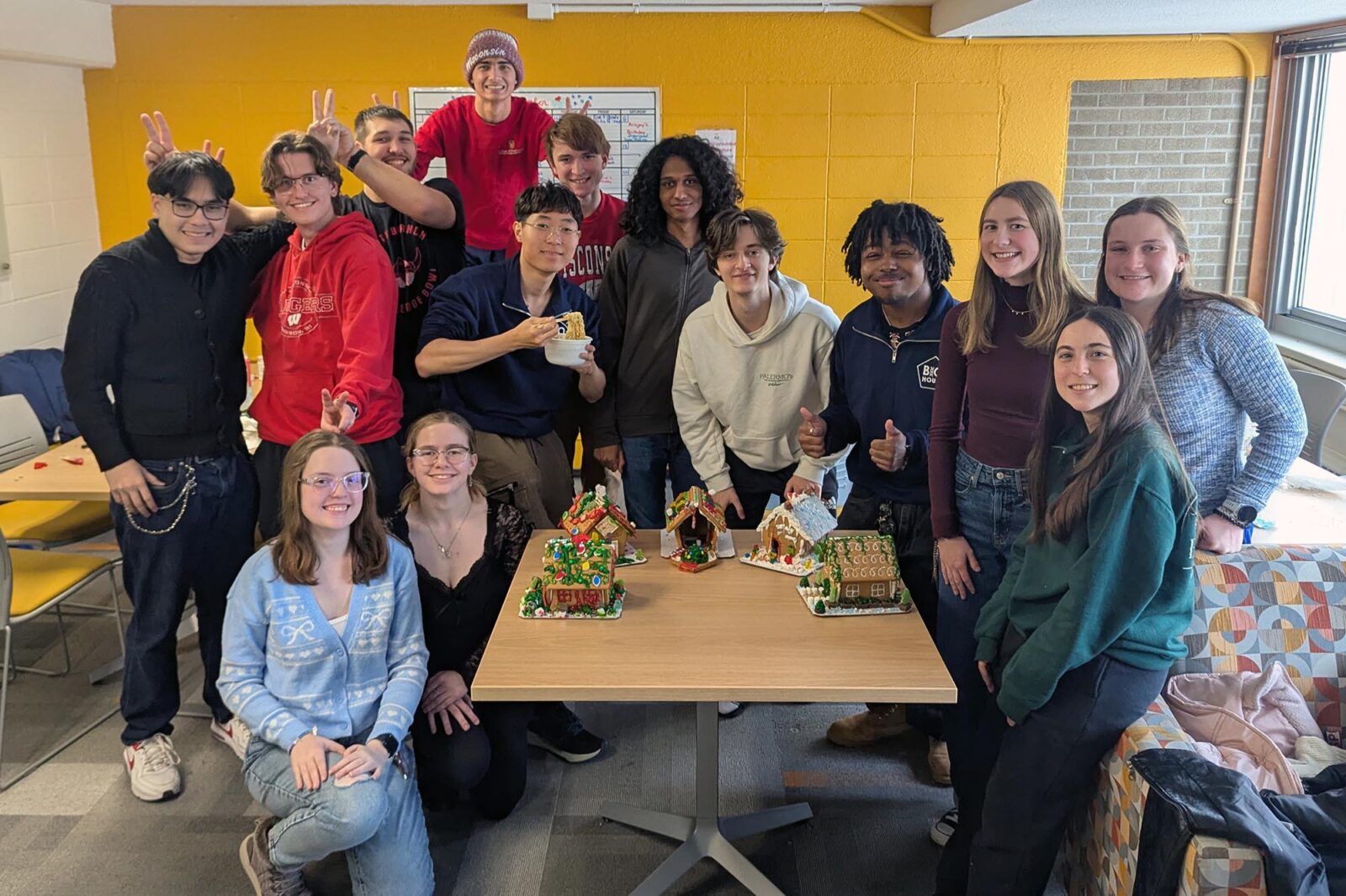 A group of people showing their gingerbread house creations.