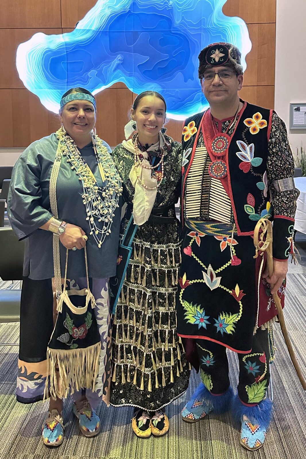 Three people posing in traditional Native American dress.