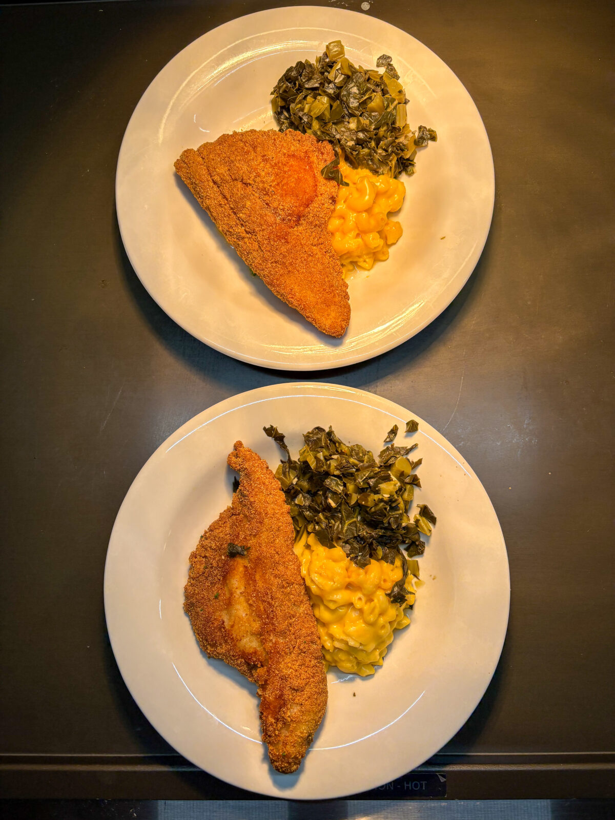 Two plated meals with chicken, collard greens, and mac and cheese